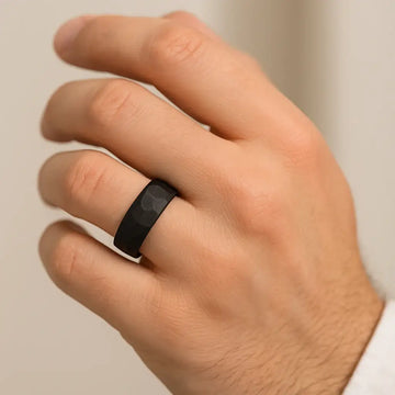 Black hammered-finish tungsten ring shown worn on a hand