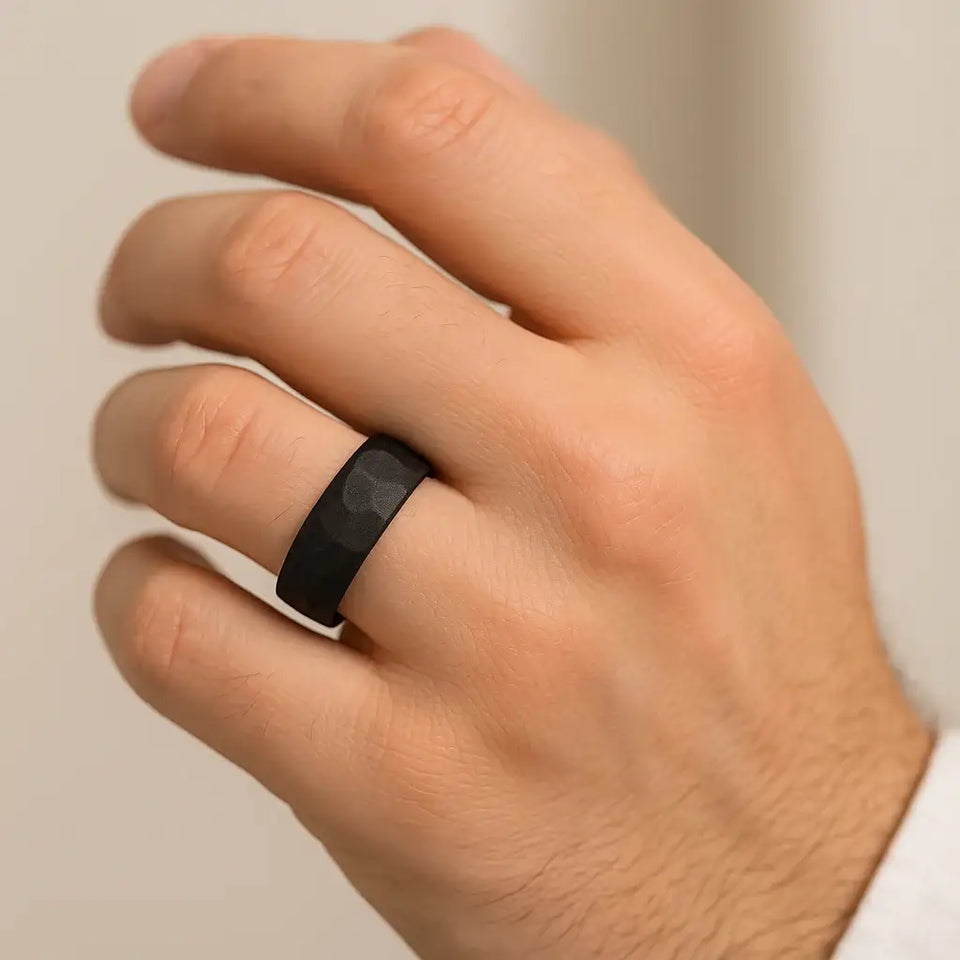 Black hammered-finish tungsten ring shown worn on a hand