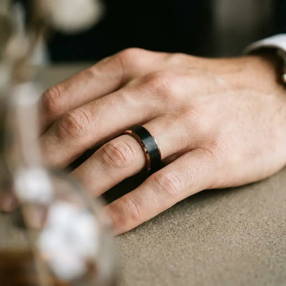 Tungsten ring with brushed black center band and polished beveled edges worn on finger.