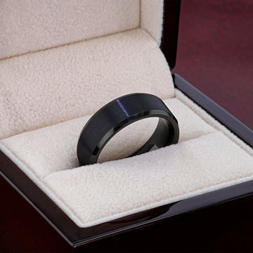 Black brushed tungsten carbide ring placed in a cream jewelry box