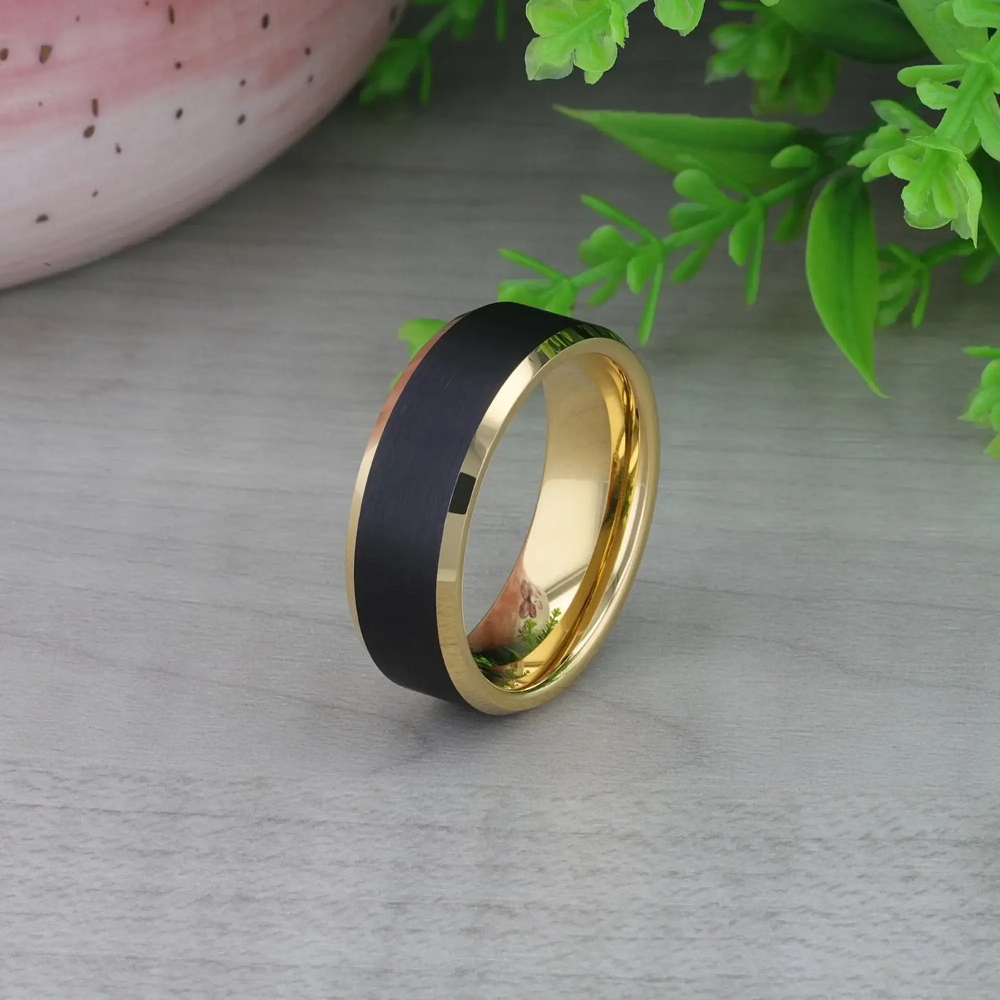 Top-down view of ring on white fabric, emphasizing straight black center stripe and gold sides