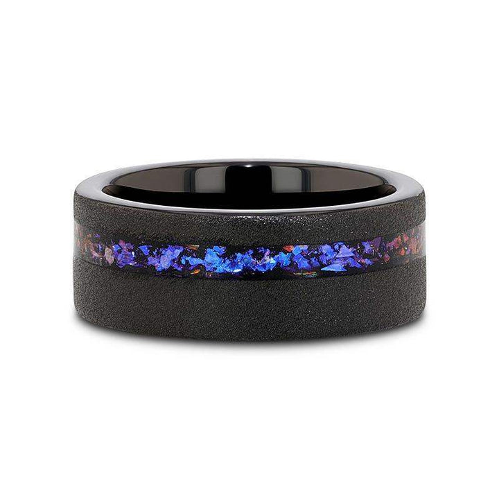Flat lay of the 8mm sandblasted black tungsten ring highlighting the continuous crushed alexandrite and blue-purple goldstone inlay