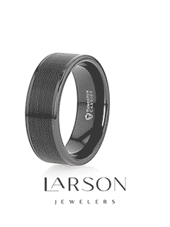 Lifestyle image of the black tungsten ring on a light surface with greenery in the background