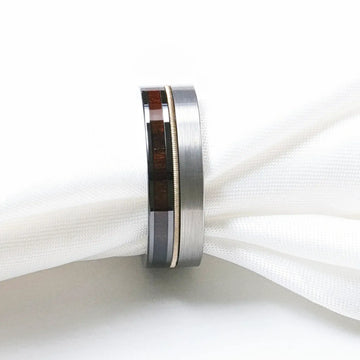 Close-up of the SLATE hybrid ring against white fabric, showing brushed tungsten exterior and ebony wood inlay
