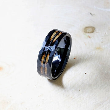 Angled tabletop shot of the ring with glossy black interior, wood inlay, and guitar string