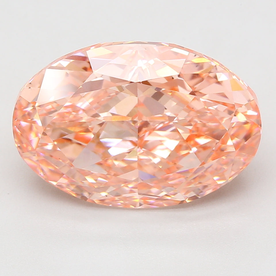Oval-cut lab-grown diamond with peach-pink coloring and faceted surface, displayed against a light gray background.