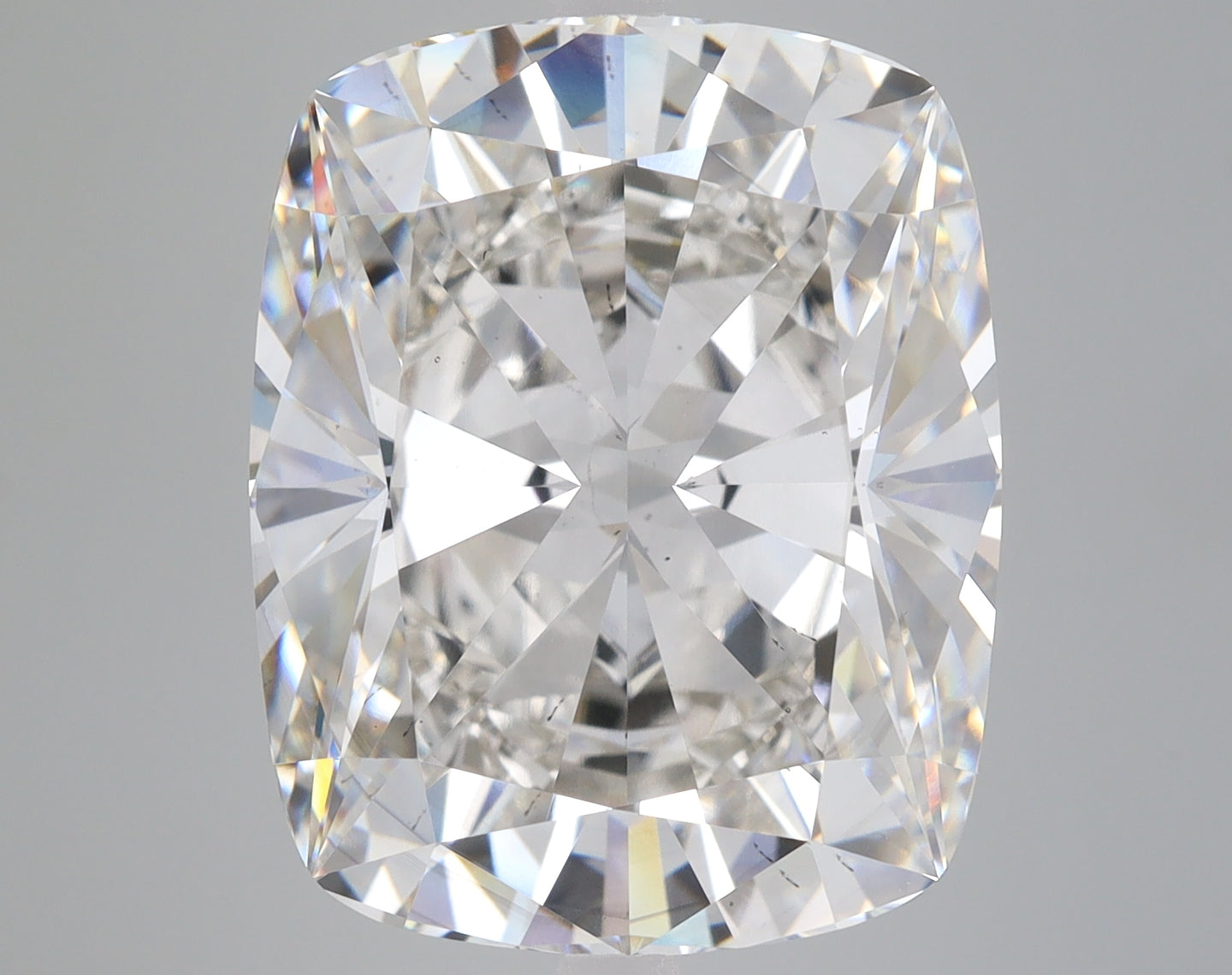 Colorless cushion-cut loose diamond with faceted surface and light refraction displayed on gray background.