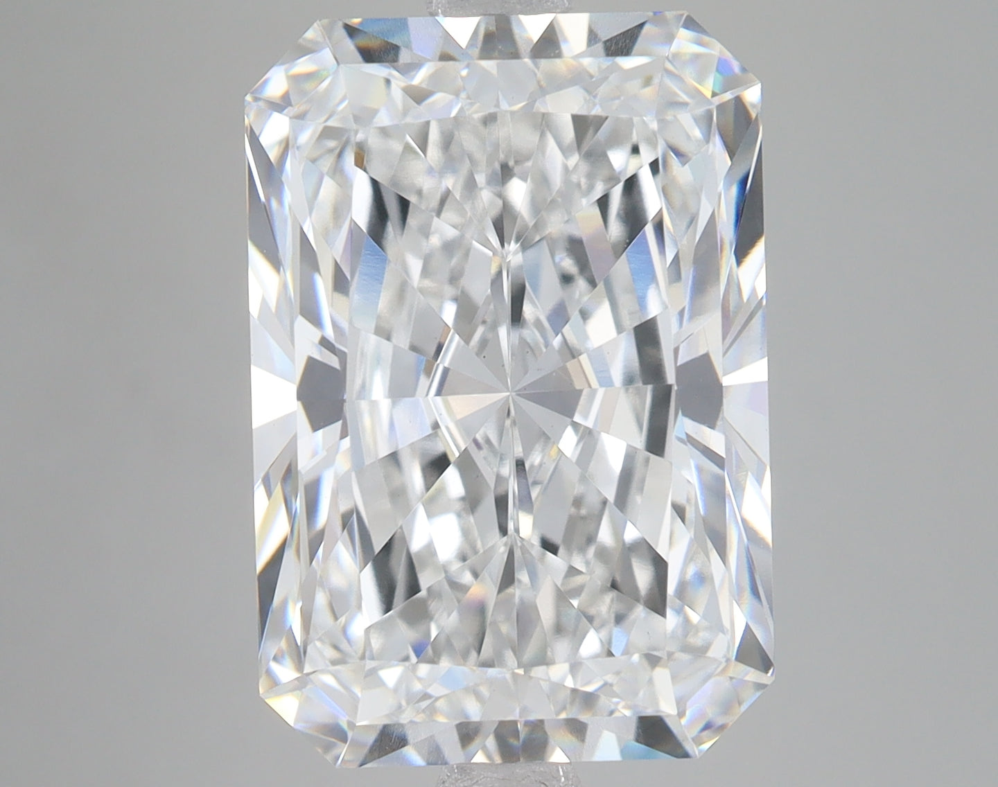 Radiant cut loose diamond with faceted surfaces displaying light refraction on neutral background.