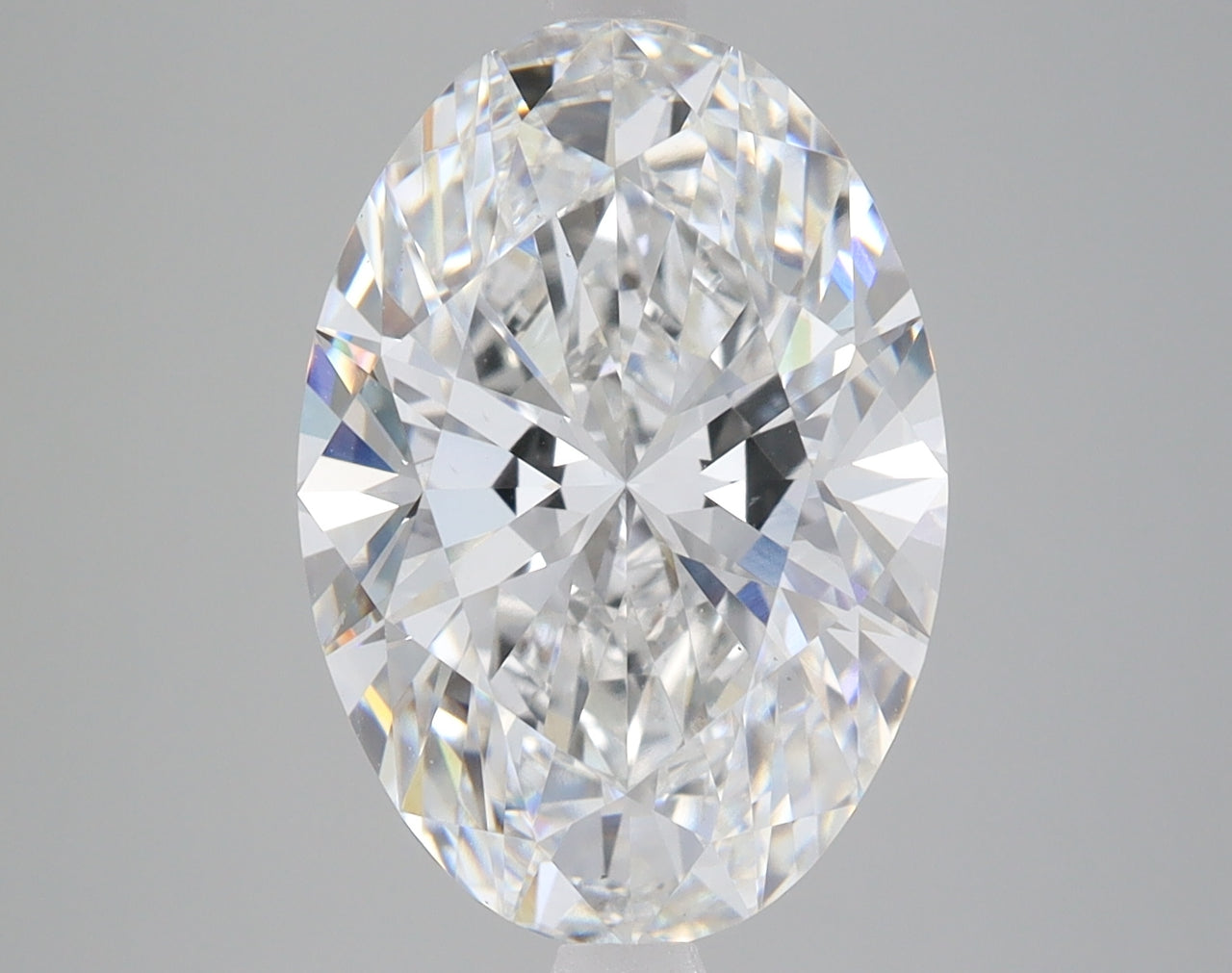 Oval-cut clear lab-grown diamond with faceted surface and light refraction on gray background.