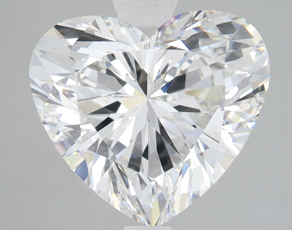 Heart-shaped colorless lab-grown diamond with faceted surfaces and light refraction on gray background.