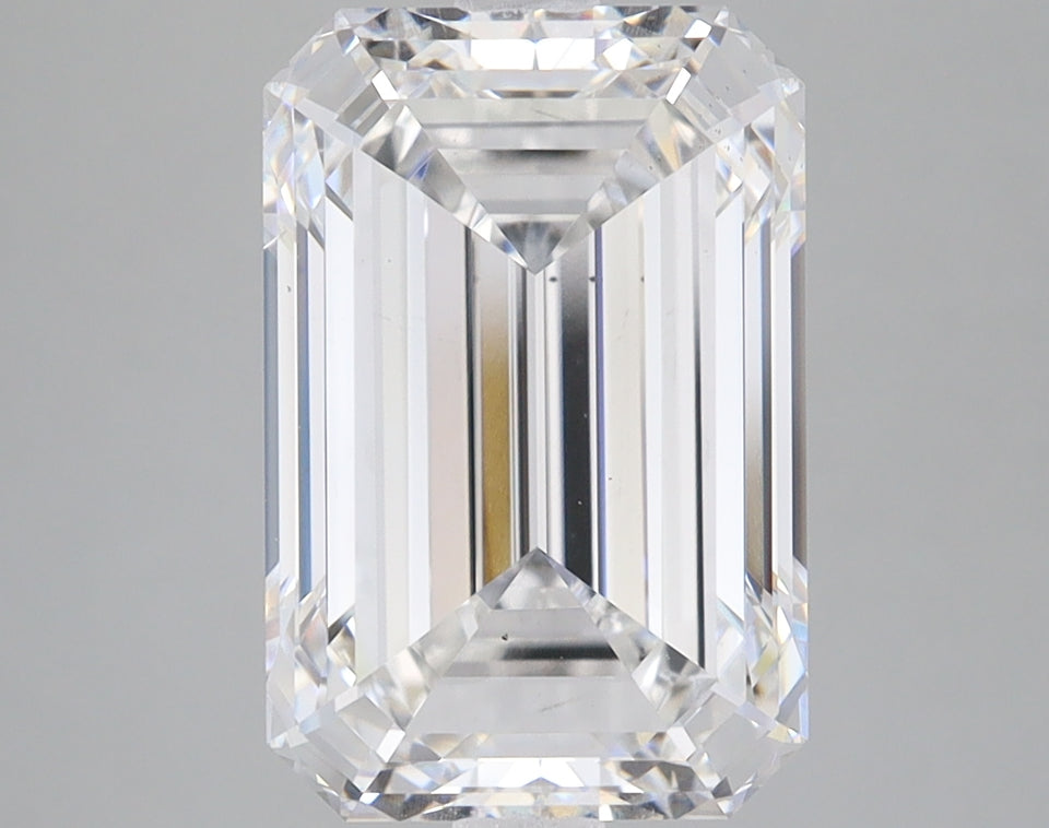 Colorless emerald-cut loose stone with faceted sides and reflective surfaces on neutral background.