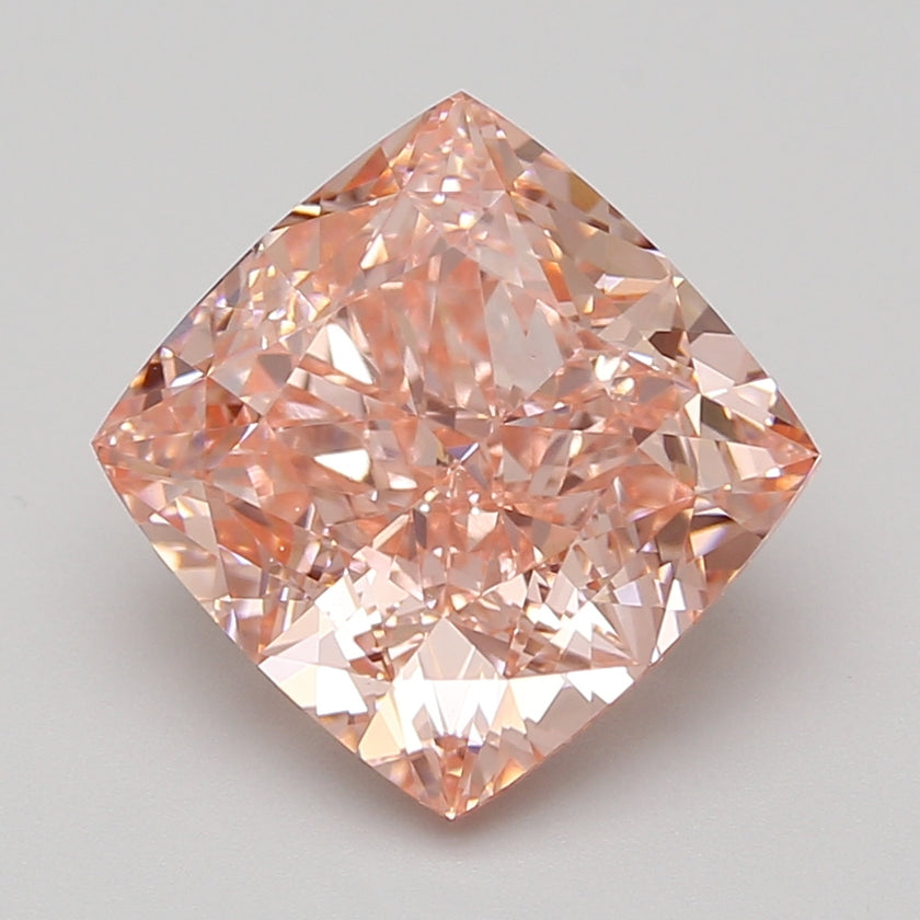 Cushion-cut lab-grown diamond with peachy-pink hue displaying faceted surface and light reflections.