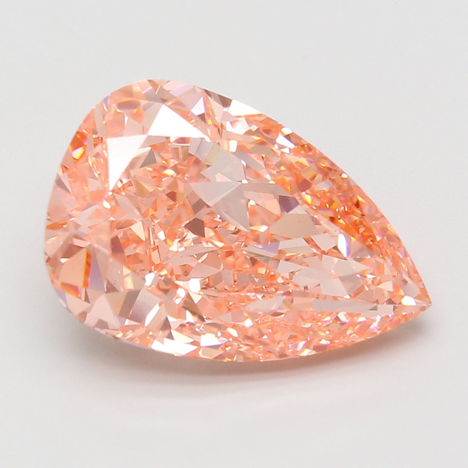 Pear-shaped lab-grown diamond with peach-pink coloring and faceted surface displaying light refraction.
