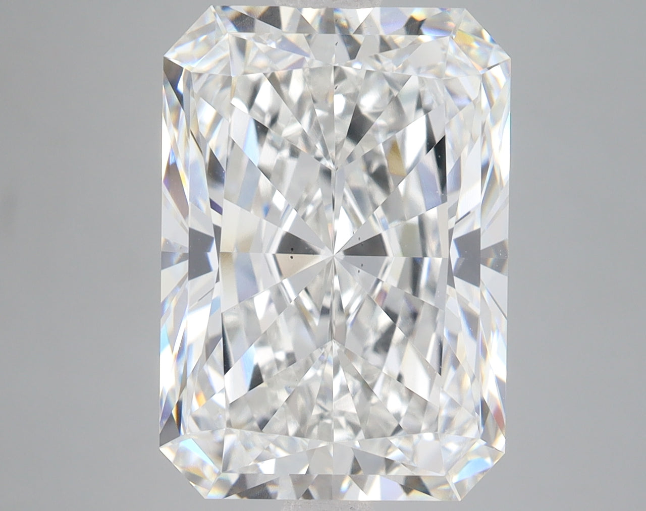 Clear radiant-cut diamond displaying faceted surfaces with light refraction on neutral background.