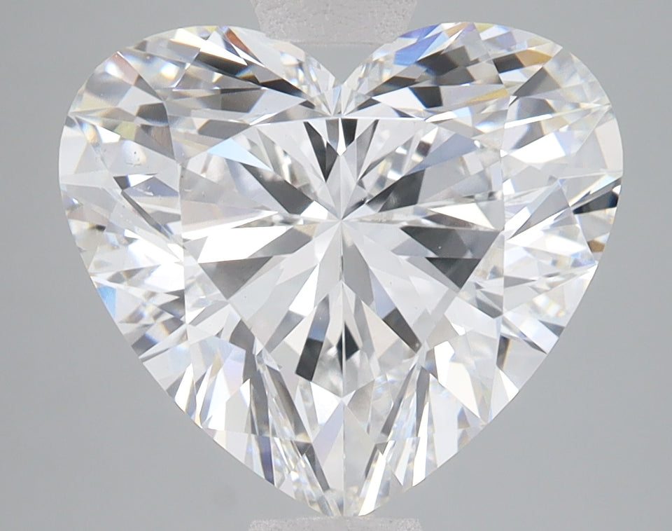 Heart-shaped lab-grown diamond with faceted surface and light refraction on gray background.