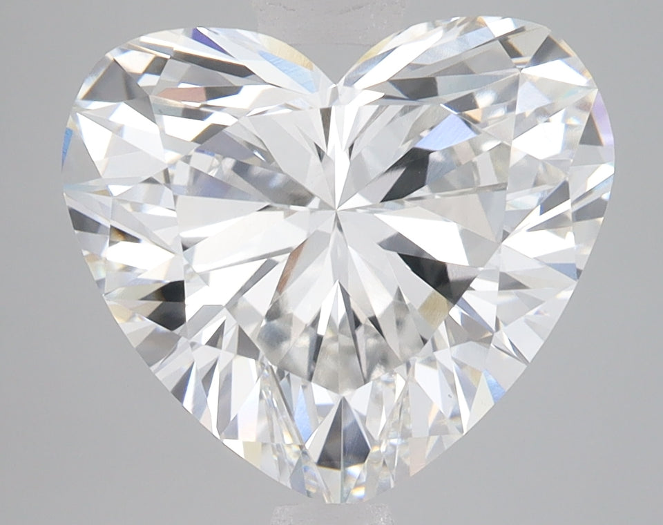 Heart-shaped faceted diamond with brilliant light refraction on gray background.