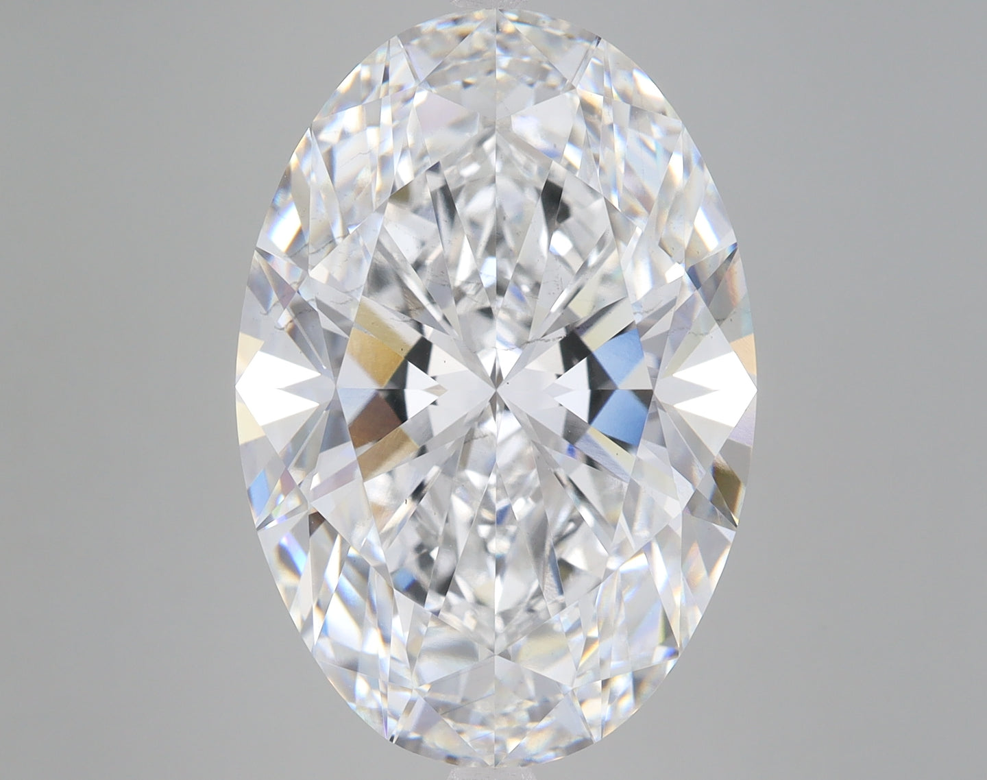 Oval-cut lab-grown diamond with faceted surface reflecting light in multiple colors against gray background.