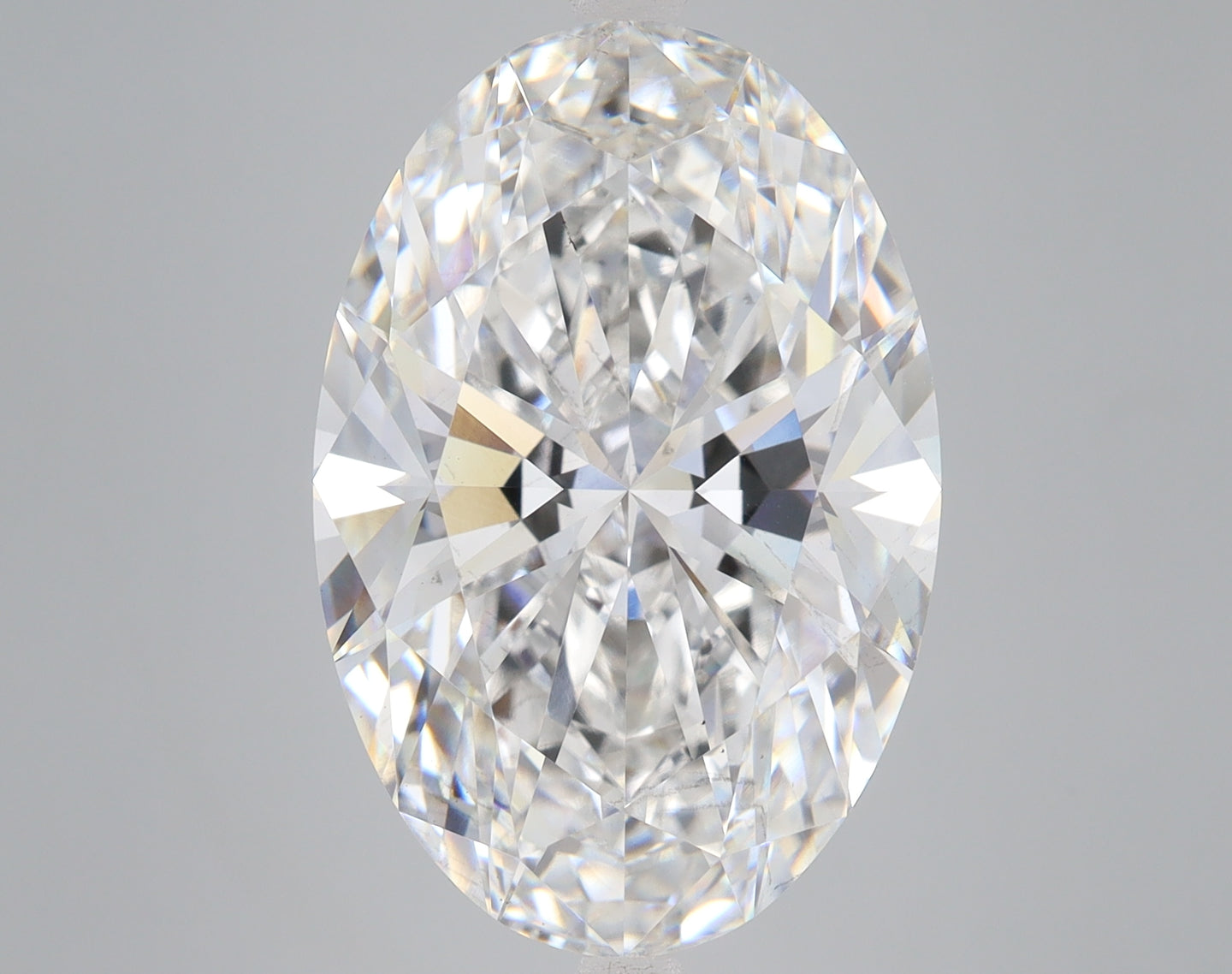 Oval-cut lab-grown diamond with faceted surfaces reflecting light, displayed against a neutral gray background.