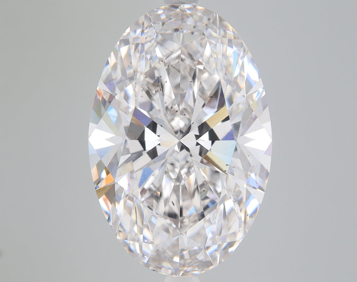 Colorless oval-cut lab-grown diamond with faceted surfaces and light refraction on neutral background.