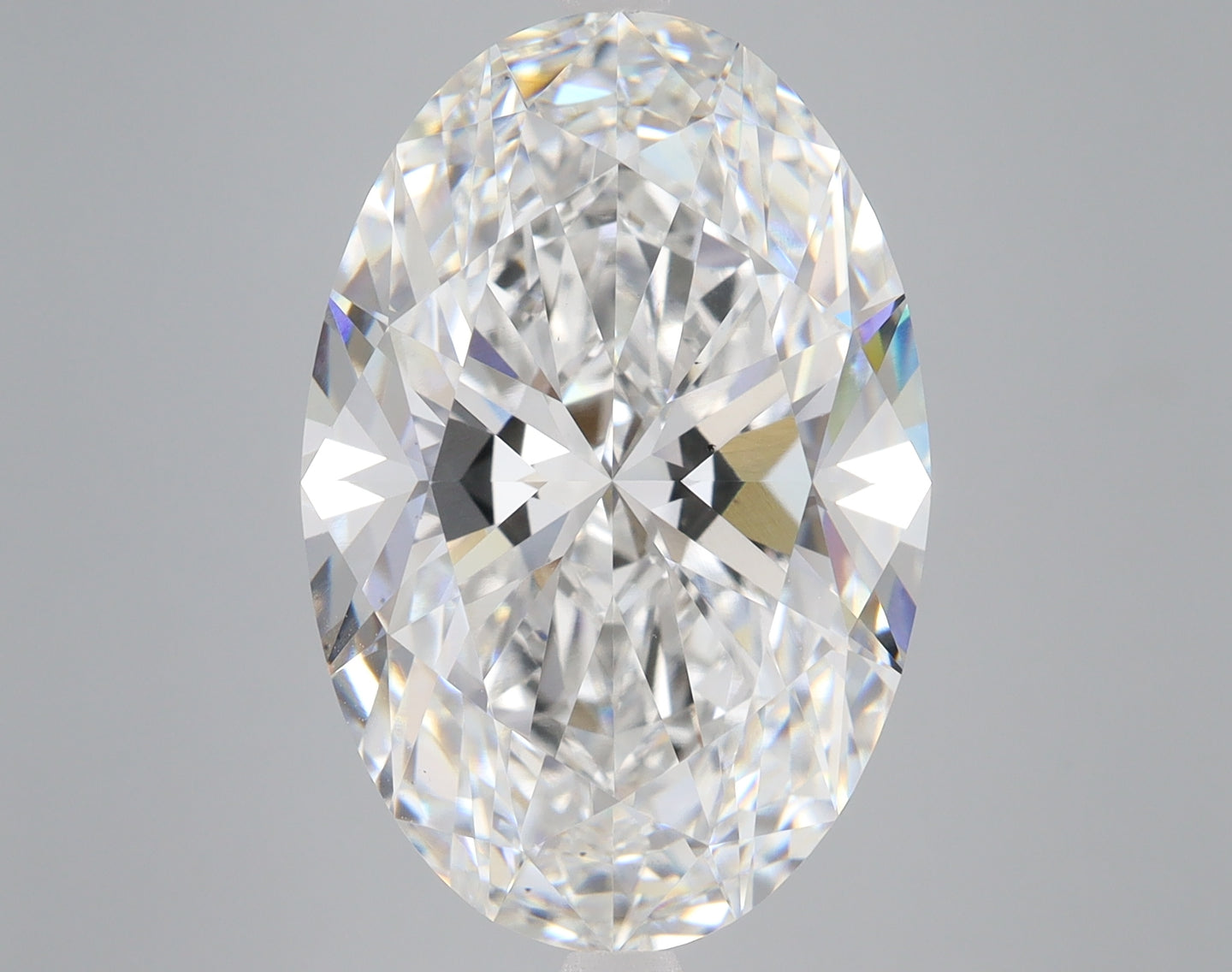 Oval-cut lab-grown diamond with faceted surfaces reflecting white and colored light against a gray background.