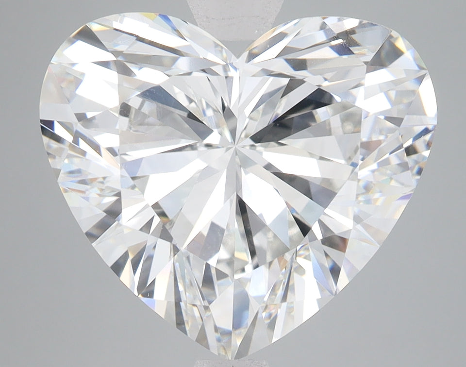 Heart-shaped clear lab-grown diamond with faceted surfaces reflecting light, displayed against gray background.