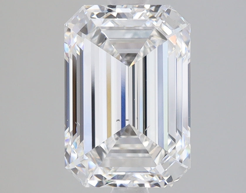 Clear emerald-cut diamond with faceted surfaces and light refraction on neutral gray background.