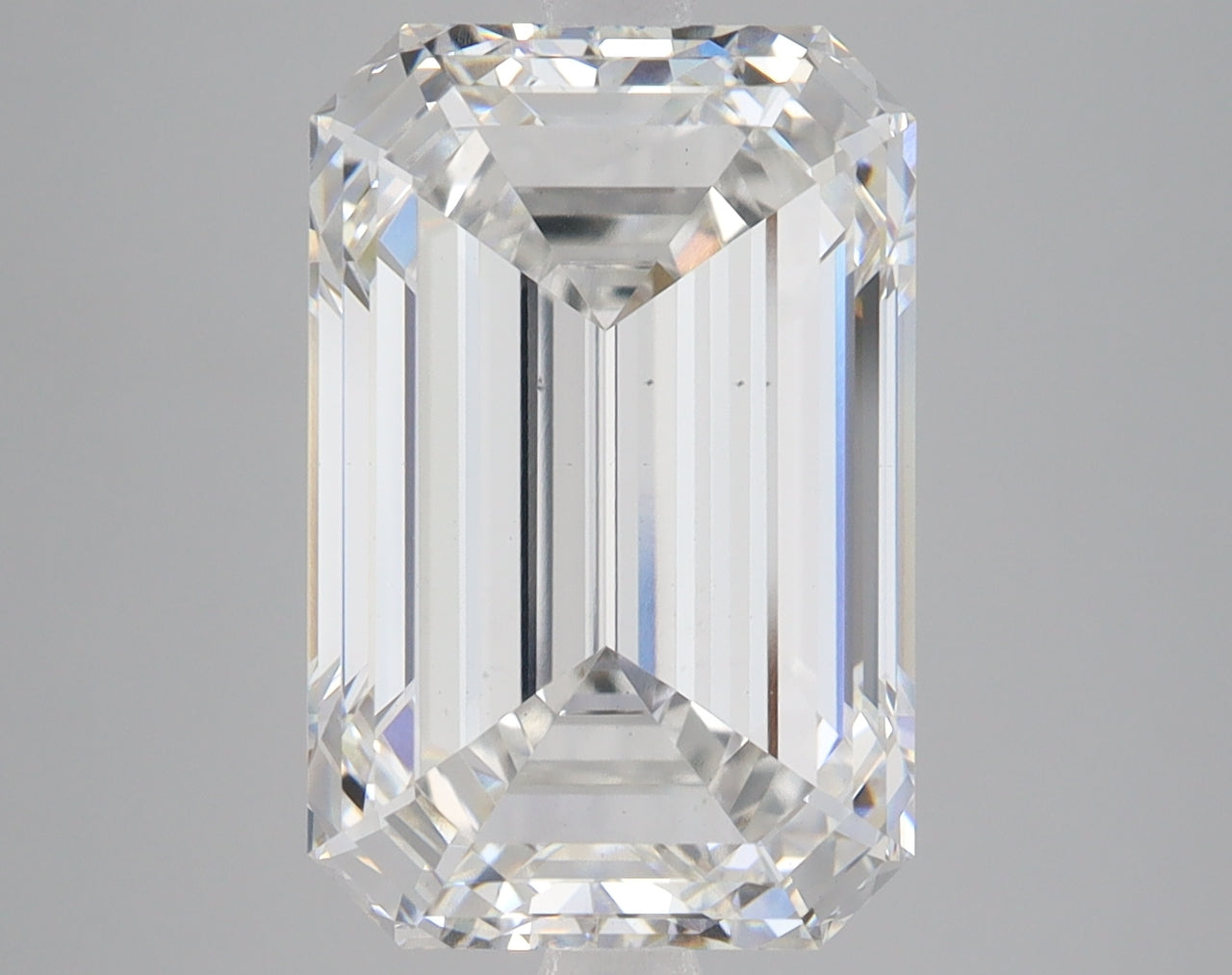 Emerald-cut lab-grown diamond with faceted surfaces and light refraction on gray background.