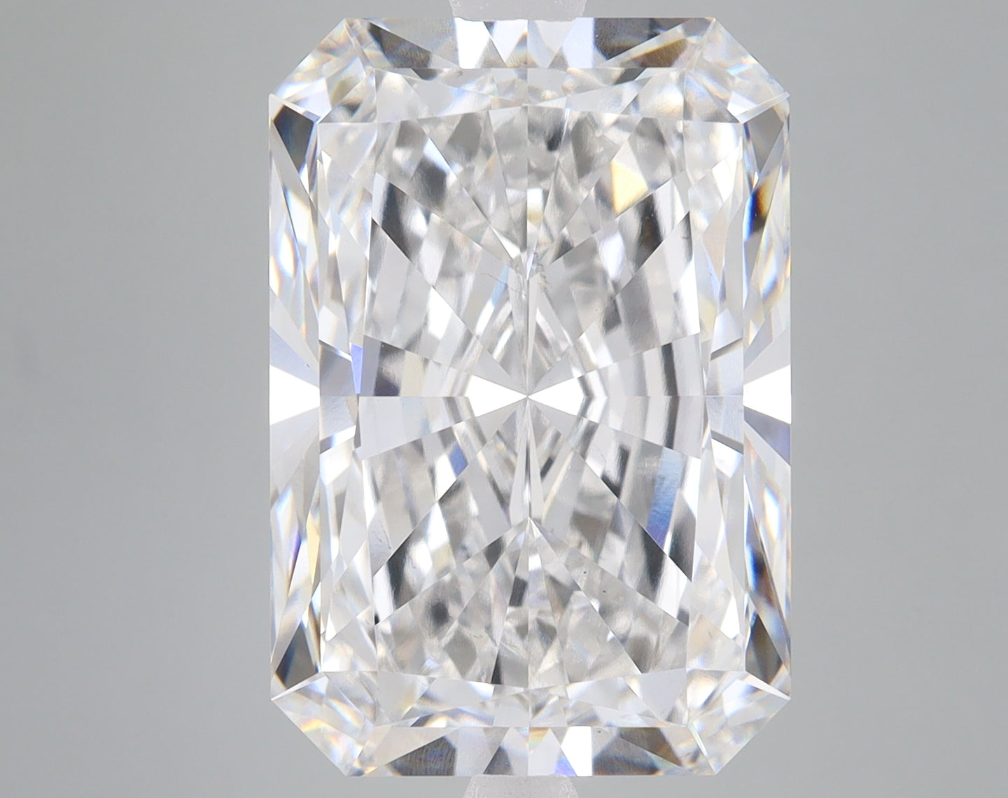 Radiant cut loose diamond with faceted surface and light reflections on gray background.