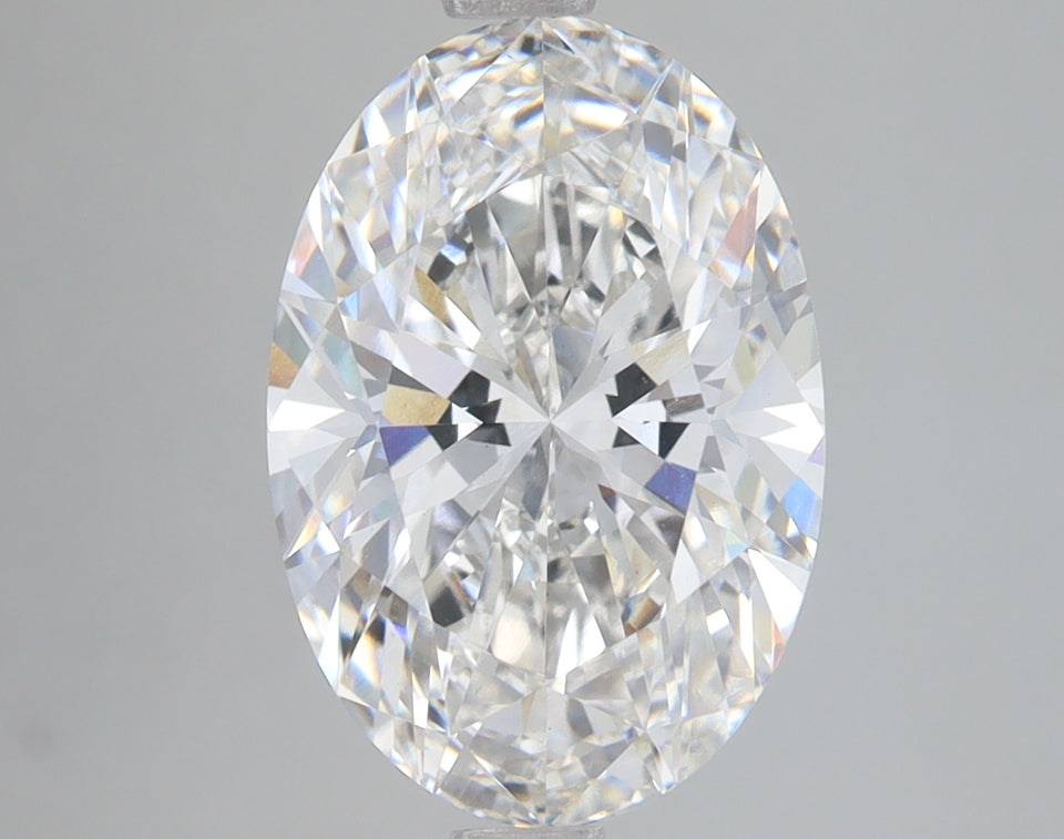 Oval-cut lab-grown diamond with faceted surfaces and light reflections on neutral gray background.