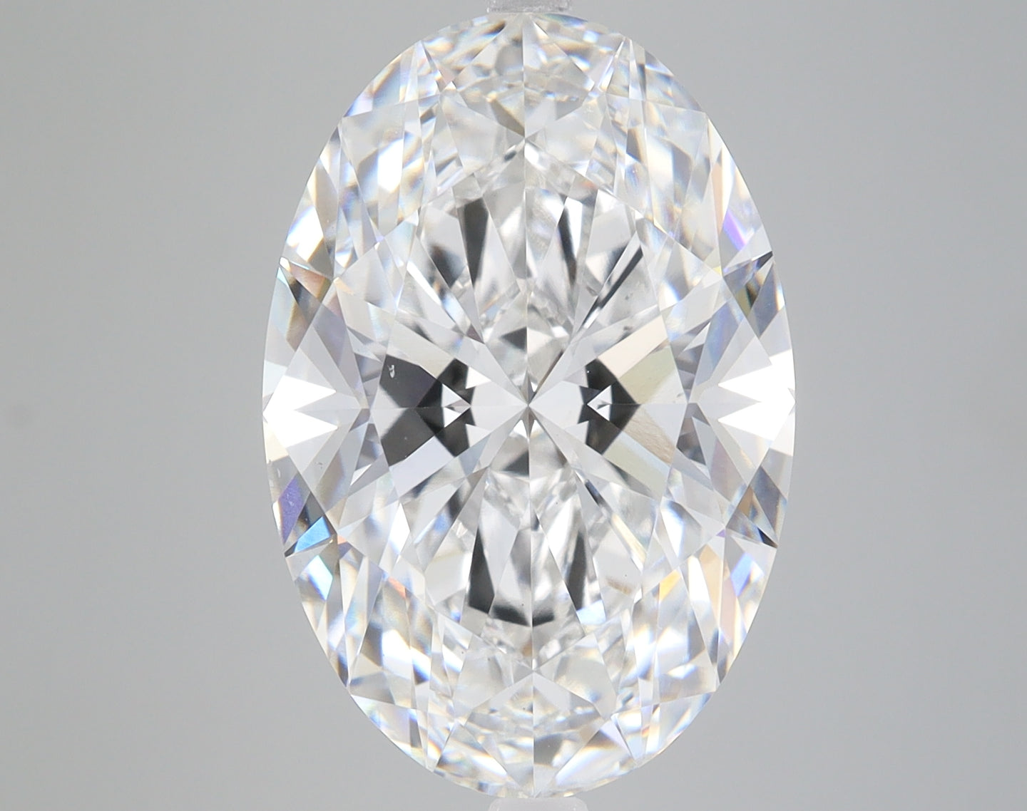Oval-cut lab-grown diamond with faceted surface reflecting light, displayed against neutral gray background.