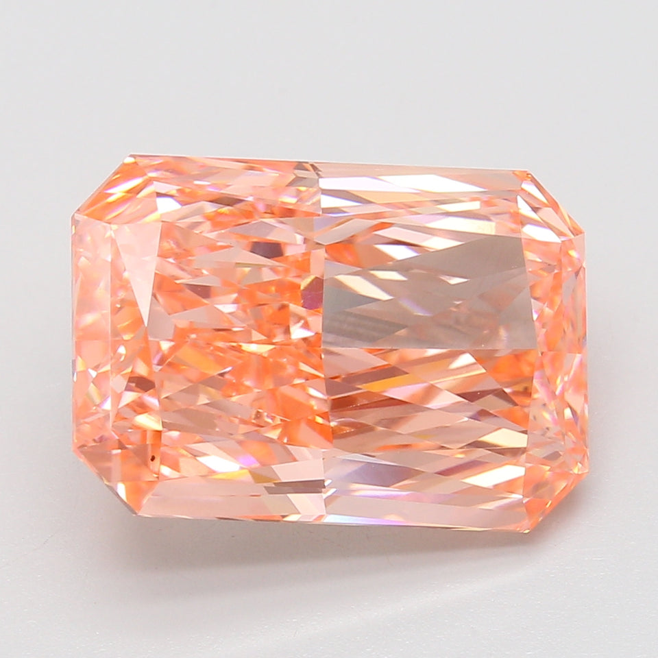 Radiant cut lab-grown diamond with peachy-pink hue and faceted surfaces reflecting light.