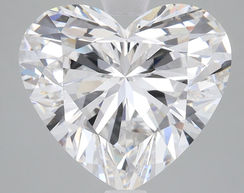 Heart-shaped lab-grown diamond with faceted surface and light refraction displayed on gray background.