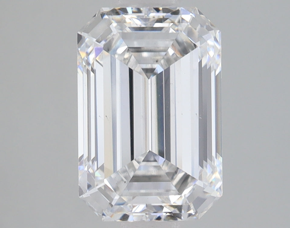 Emerald-cut clear diamond with faceted edges and brilliant light reflection on neutral background.