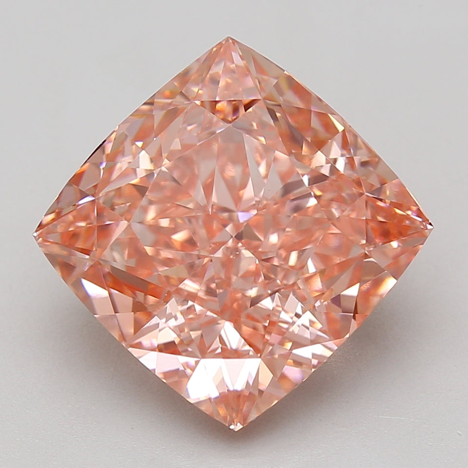 Cushion cut lab-grown diamond with peachy-pink hue, faceted surface reflecting light, displayed against neutral background.