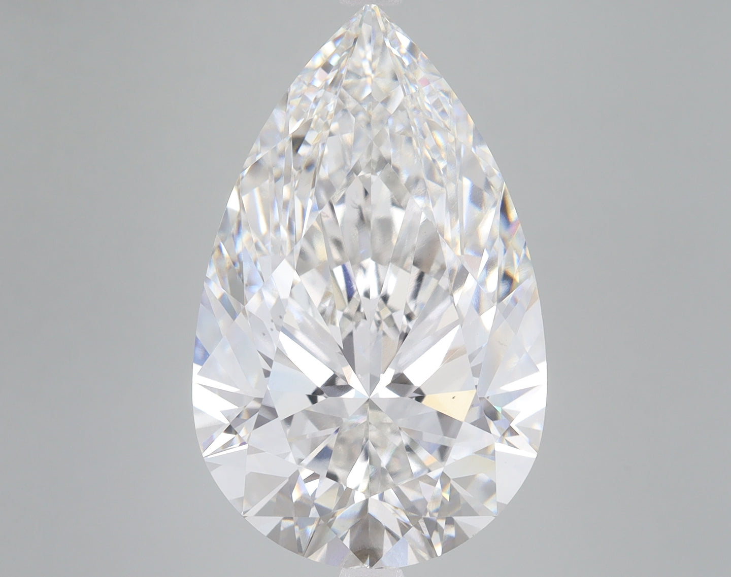 Clear pear-shaped lab-grown diamond with faceted surface and light reflections on neutral gray background.