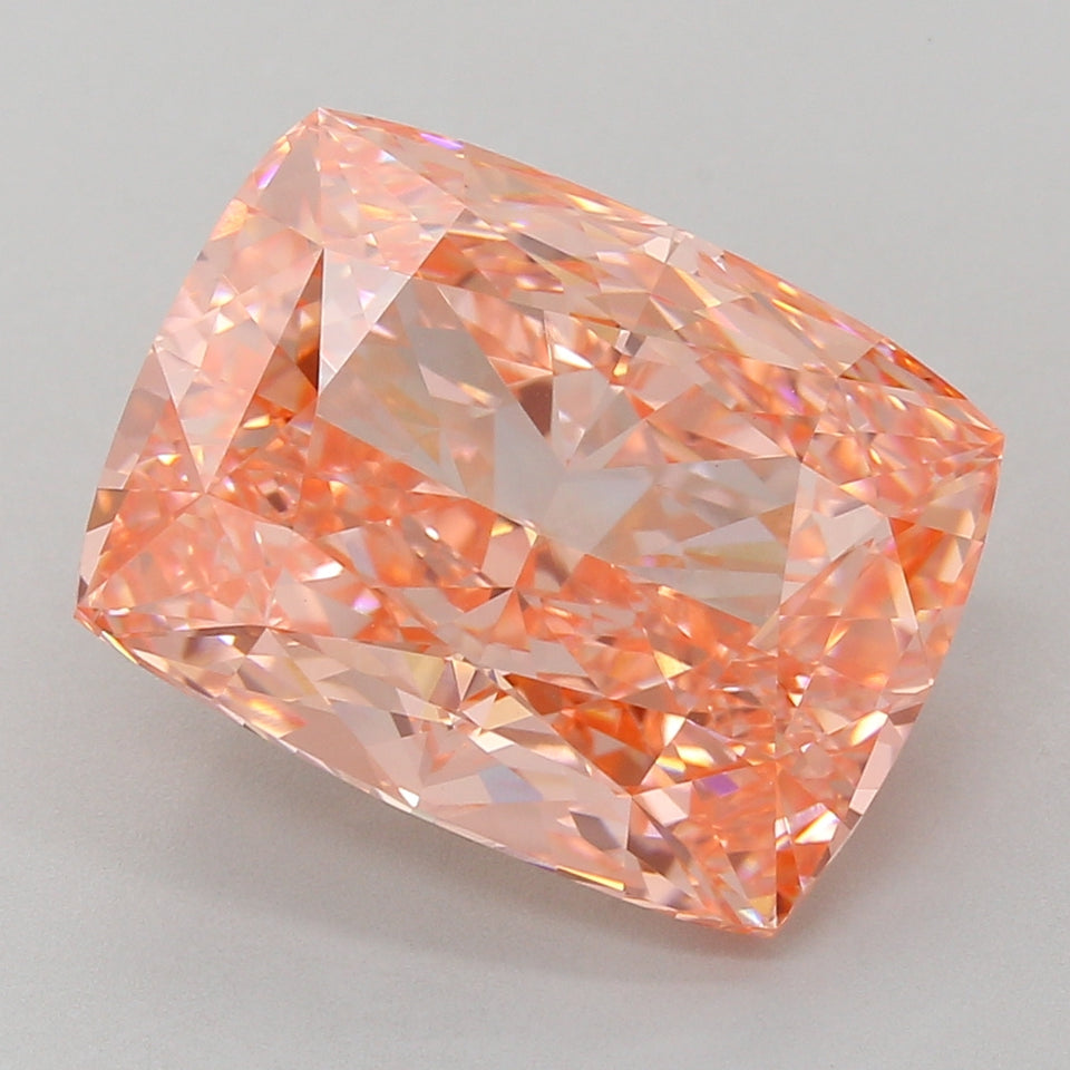 Cushion cut lab grown diamond with peachy-pink hue and faceted surfaces displaying light refraction.