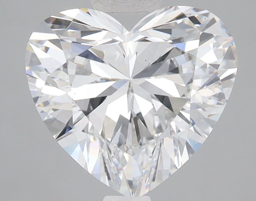 Heart-shaped lab-grown diamond with faceted surface and light refraction on gray background.
