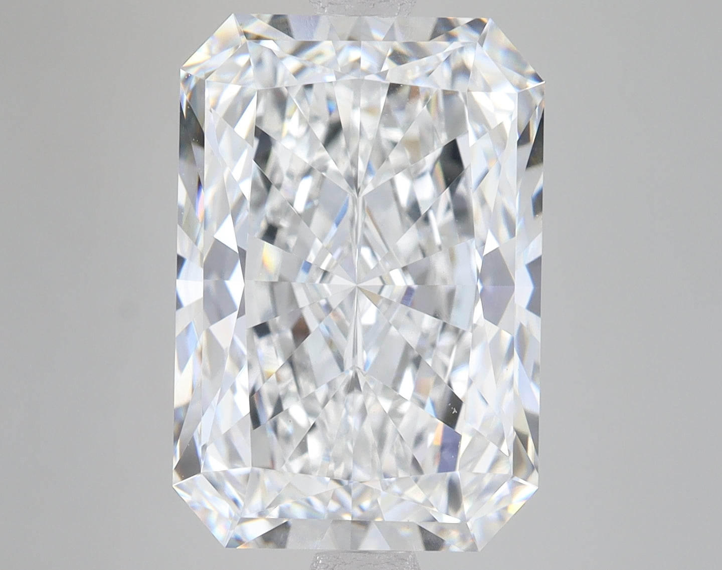 Radiant cut loose diamond with faceted surfaces reflecting light, displayed against neutral background.