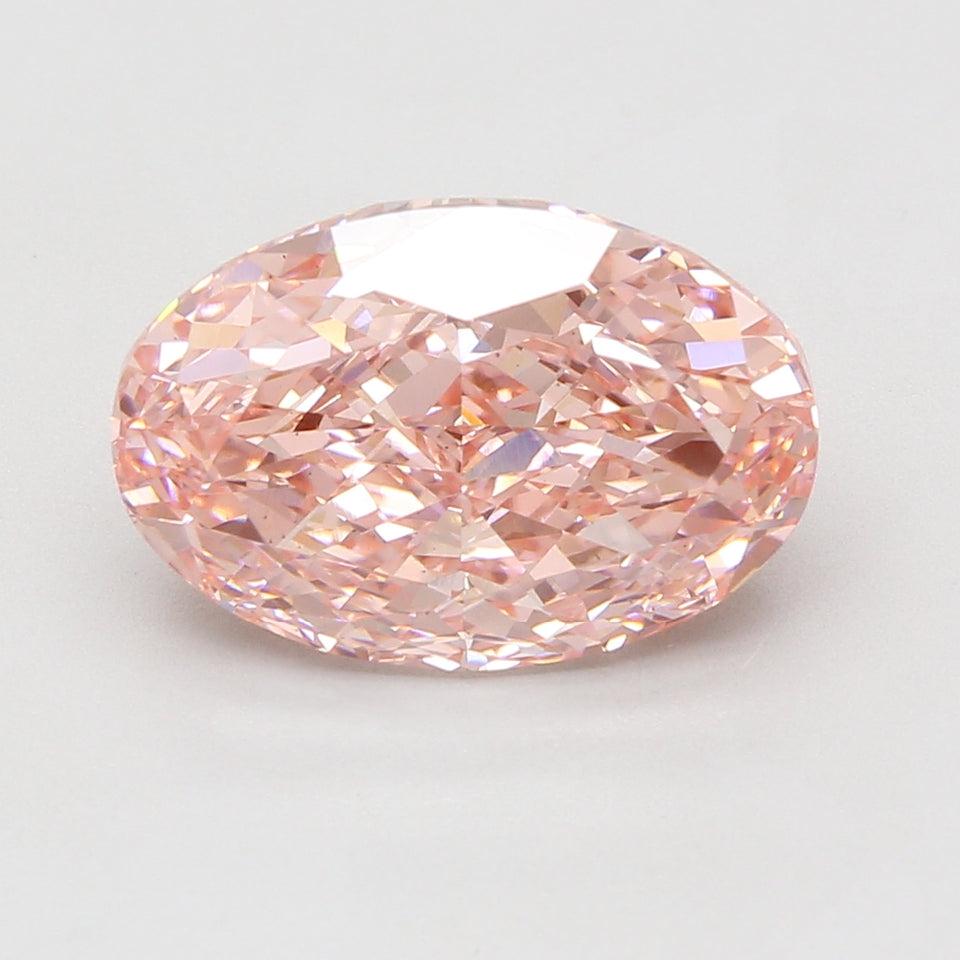 Oval-cut lab-grown diamond with pale pink hue and faceted surface, displayed against neutral background.