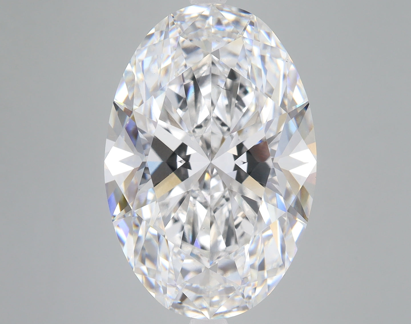Oval-cut lab grown diamond with faceted surfaces and light refraction, displayed against neutral background.