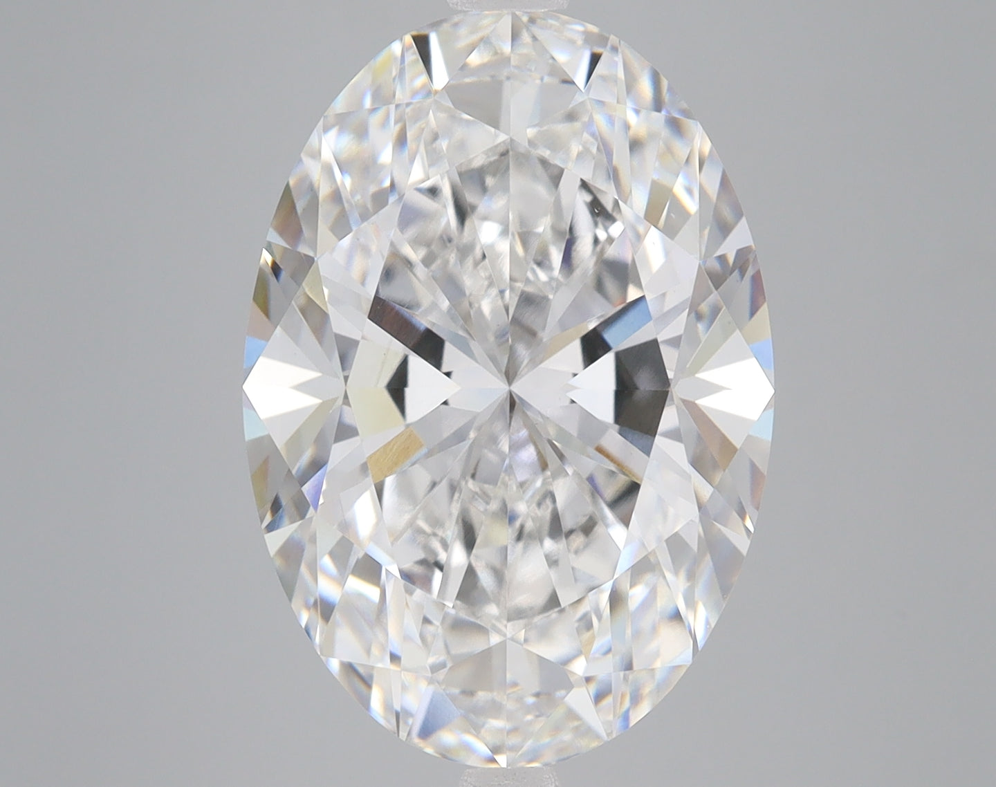 Oval-cut lab-grown diamond with faceted surface displaying light refraction, presented on neutral gray background.