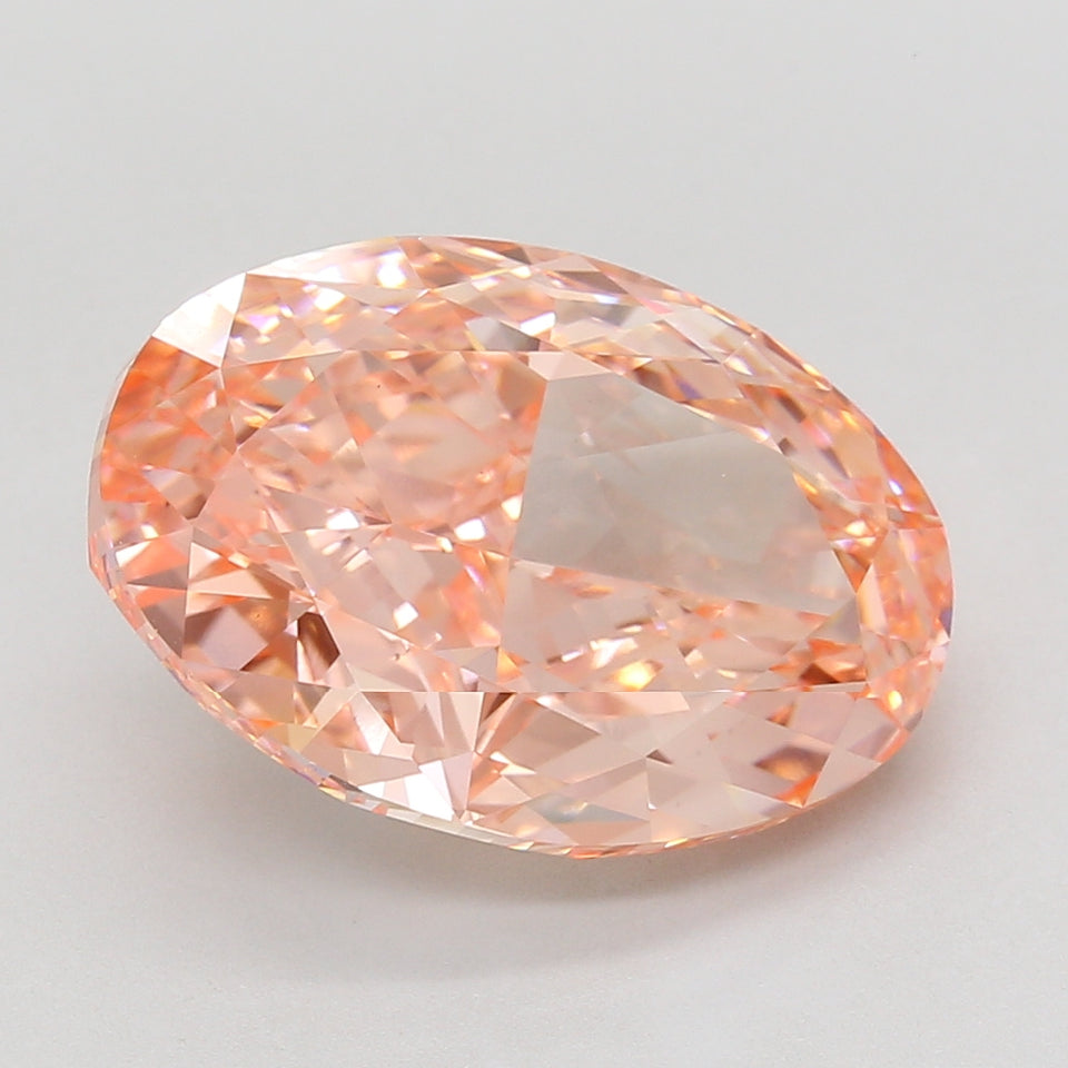Oval-cut lab-grown diamond with light peachy-pink hue and faceted surface, displayed on neutral background.