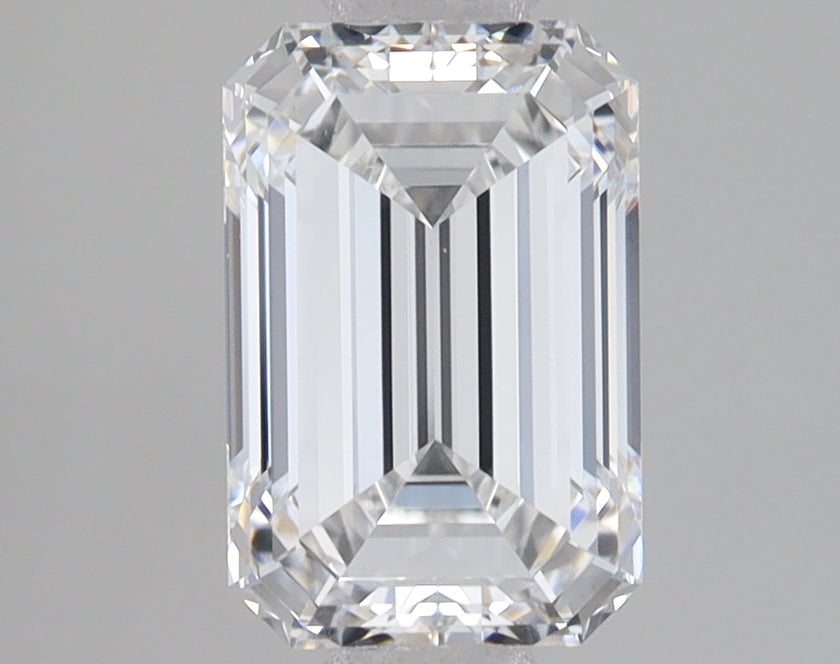 Clear emerald-cut lab-grown diamond with faceted sides and reflective surfaces on gray background.