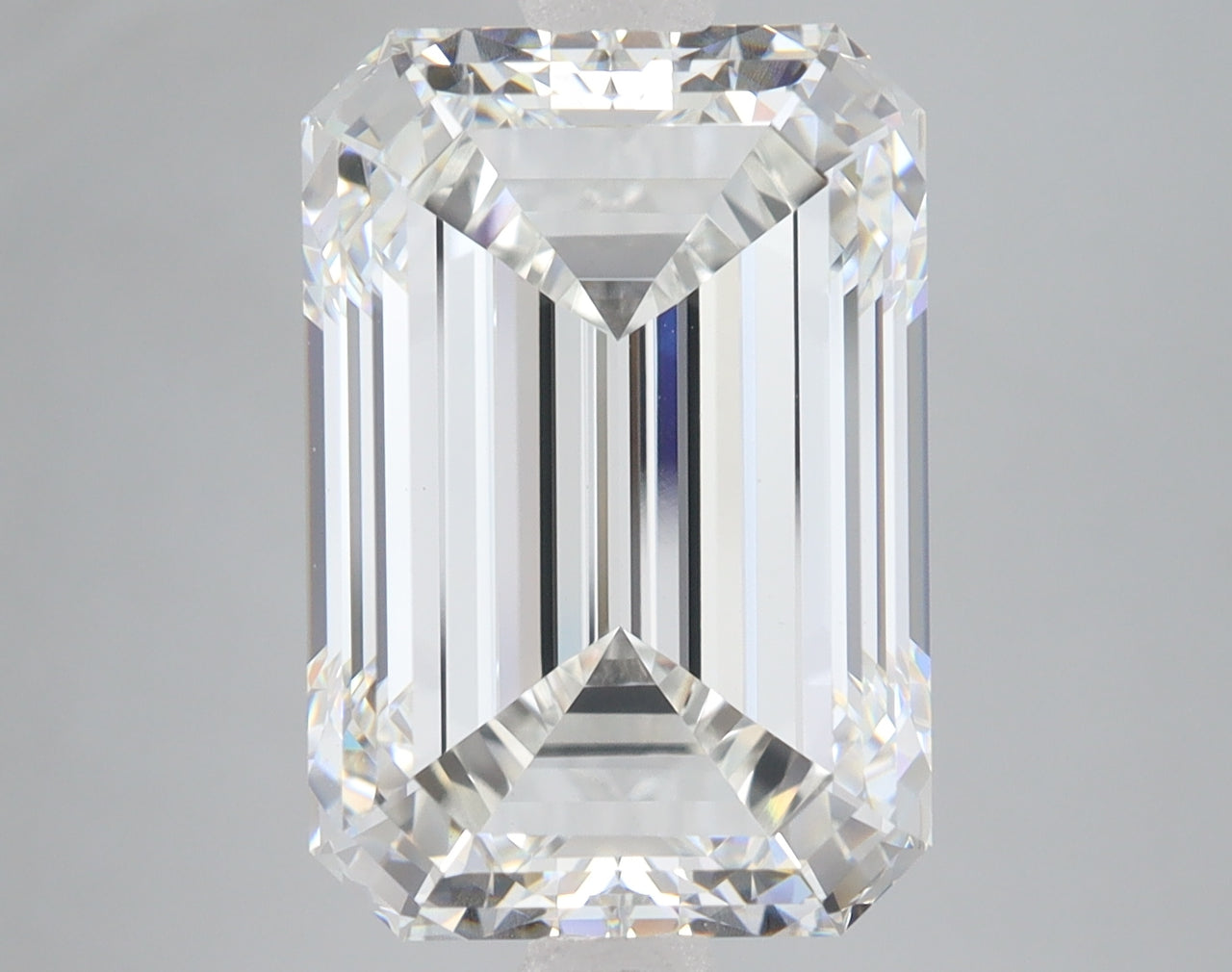 Clear emerald-cut diamond with stepped facets and bright reflections on neutral background.