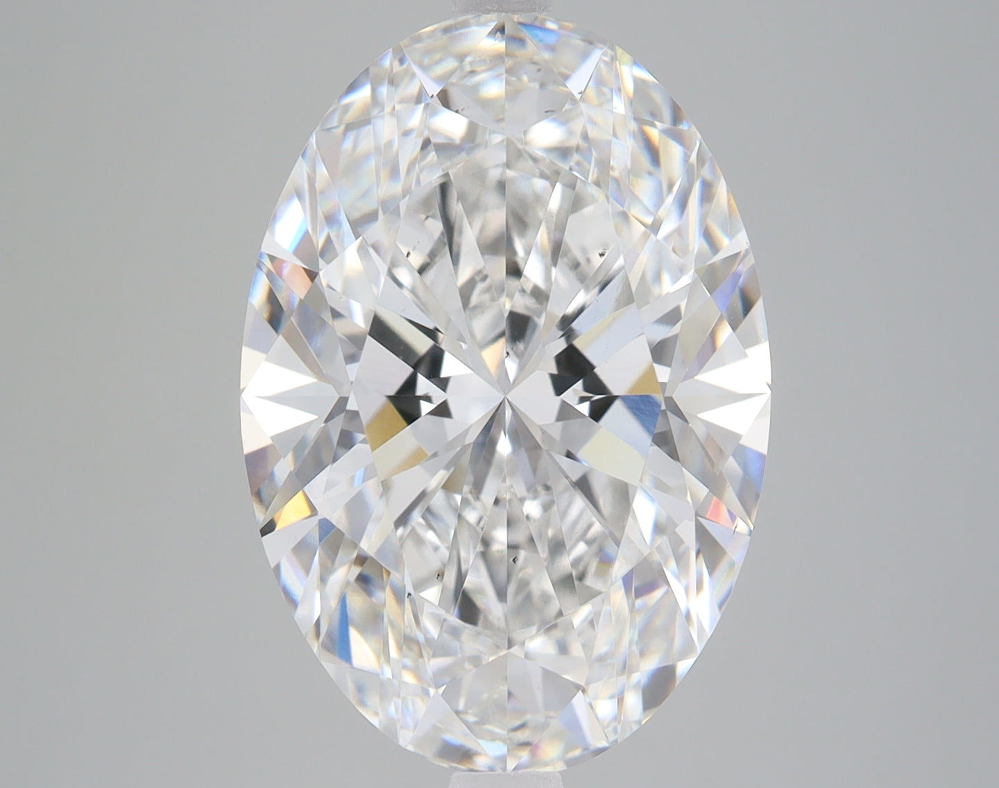 Oval-cut clear lab-grown diamond with faceted surface reflecting light, displayed against neutral background.