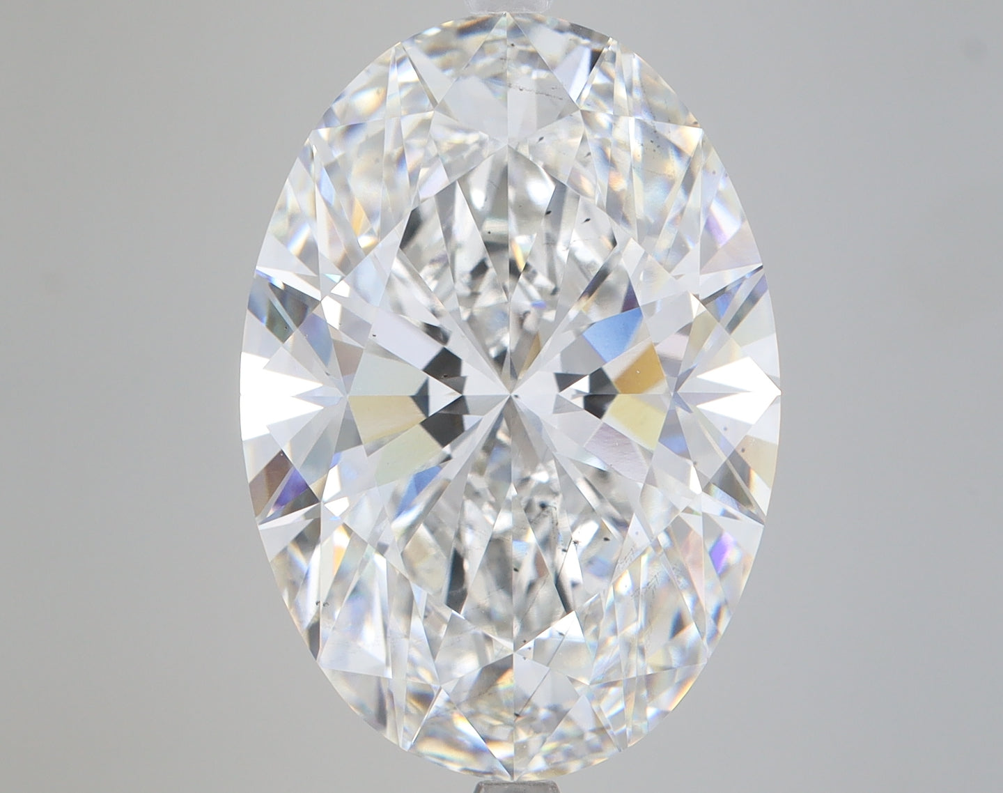 Clear oval-cut lab-grown diamond with faceted surface showing light refraction on neutral background.