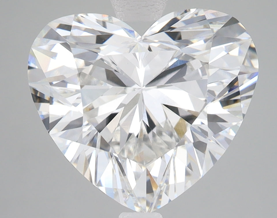 Heart-shaped lab-grown diamond with faceted cut and light reflections on gray background.