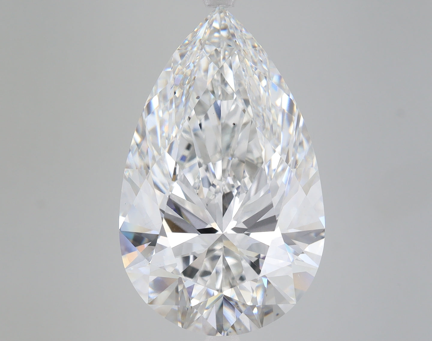Pear-shaped faceted lab-grown diamond with brilliant light reflections on neutral background.