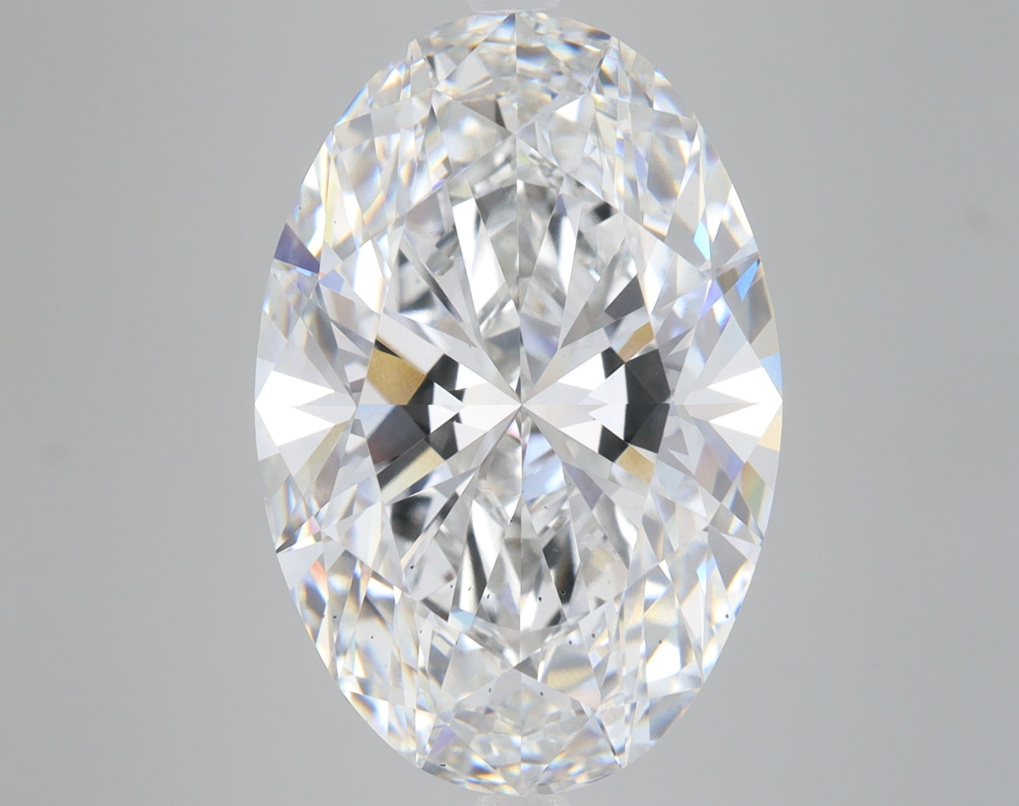 Oval-cut lab-grown diamond with faceted surface displaying light refraction and reflections on gray background.