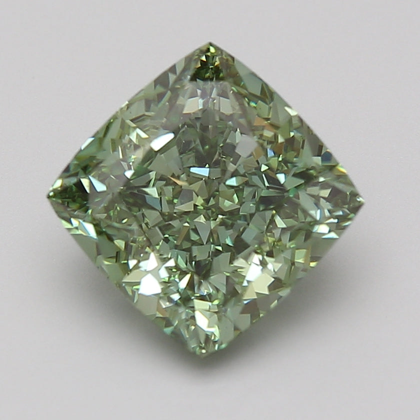 Cushion-cut lab-grown diamond with light green tint and faceted surface reflecting light, displayed on neutral background.